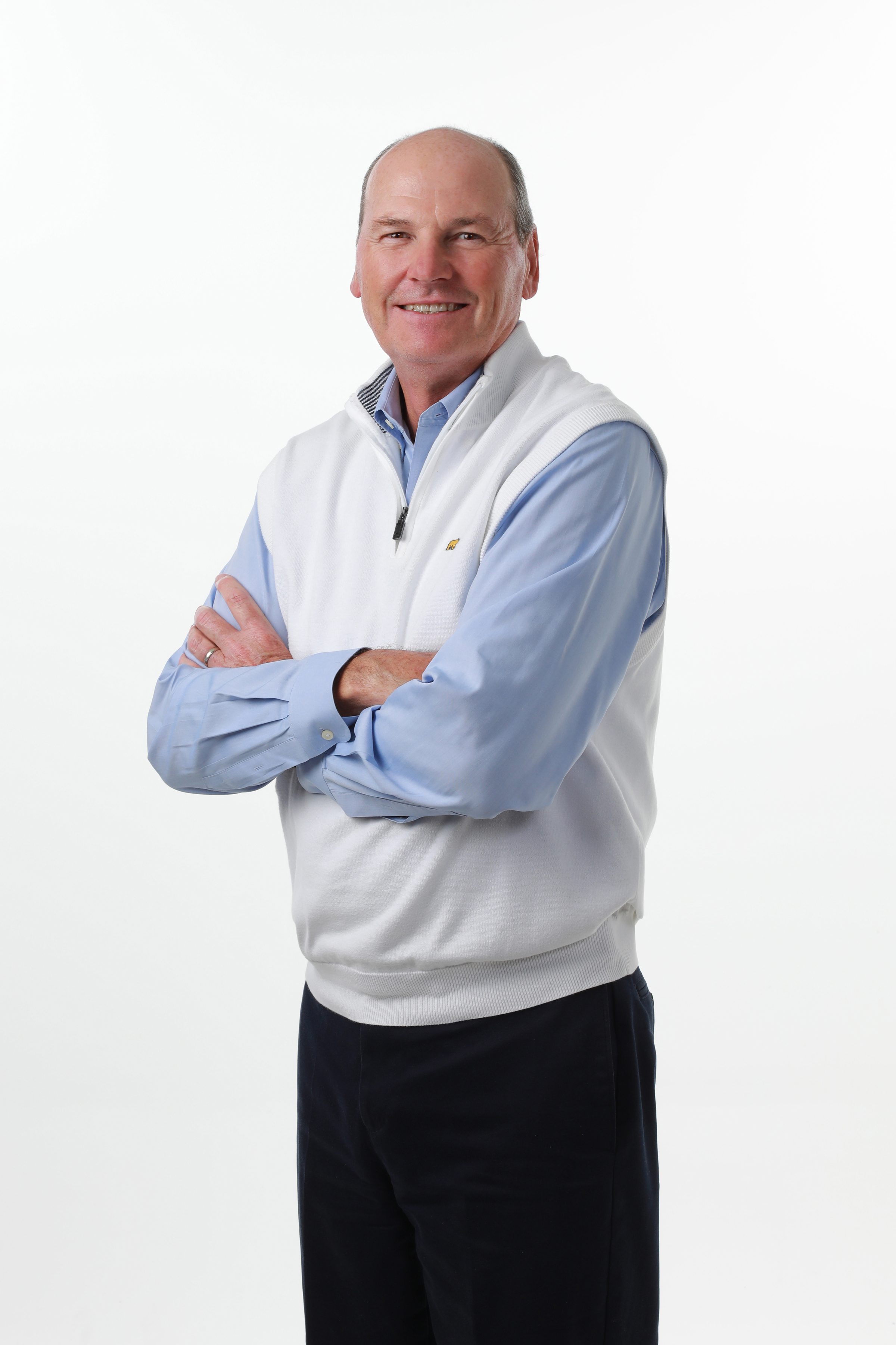 Larry Grill standing with arms folders and smiling against white background.