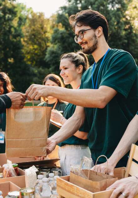 man and woman smiling and handing bags to people